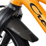 Oranssi lasten 16" jalkajarrullinen polkupyörä. Pyörässä on vakiovarusteina seisontatuki ja lokasuoja edessä. Lähikuva lokasuojasta.