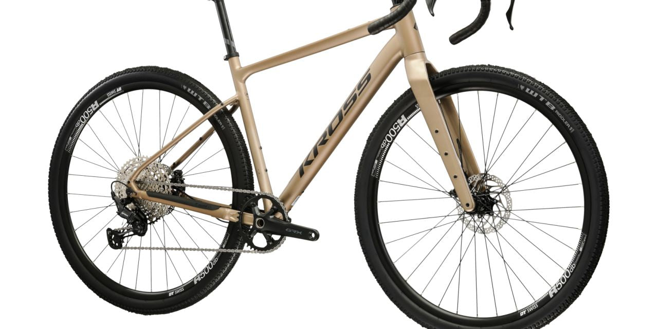 Kulta-beige 12-vaihteinen, alumiinirunkoinen ja hiilikuituihaarukkainen gravel-pyörä. Kuvattu etuviistosta.