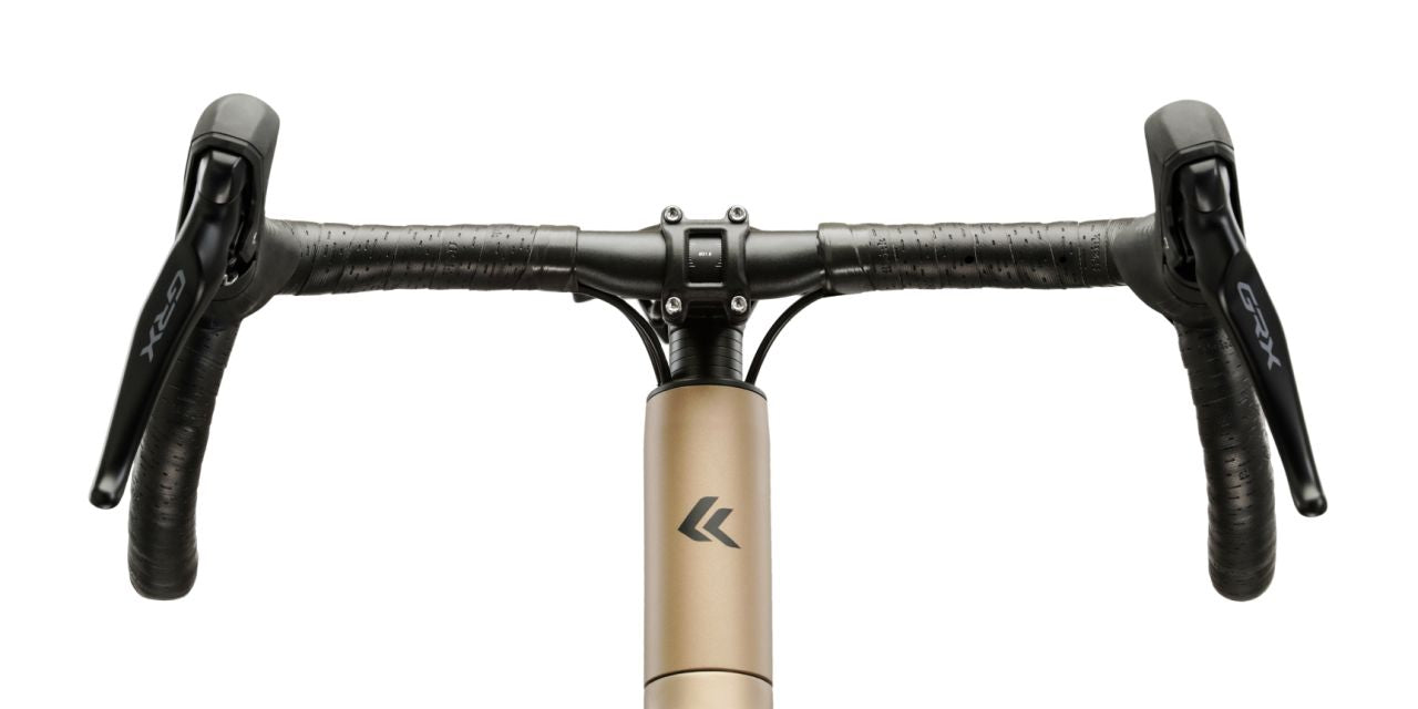 Kulta-beige 12-vaihteinen, alumiinirunkoinen ja hiilikuituihaarukkainen gravel-pyörä. Kuvattu edestä. Lähikuva tangosta , emäputkesta ja etuhaarukan yläosasta.